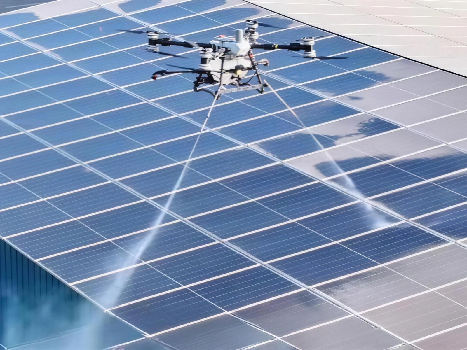 Un drone DJI nebulizza il detergente sui pannelli fotovoltaici del tetto di un capannone